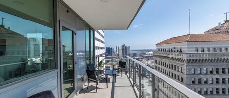 Een balkon met uitzicht op de stad, moderne meubels en een glazen deur.