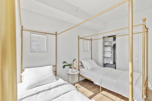 Een slaapkamer met twee bedden, een klein tafeltje met een plant en een kast met netjes opgevouwen handdoeken.