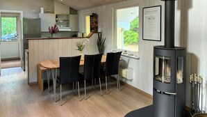 Moderni keittiö, jossa on ruokailutila, musta puukamina ja ikkuna, josta avautuu näkymä vehreään maisemaan.