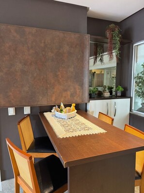 Uma área de refeições moderna com mesa de madeira, cadeiras e um centro de mesa decorativo.