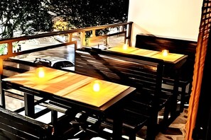 Ein Restaurant mit Außenbestuhlung, Holztischen und Blick auf die Straße.