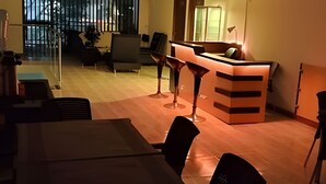 Un espacio de oficina moderno con un mostrador de recepción, dos taburetes tipo bar, una mesa de conferencias y vistas al exterior a través de amplias ventanas.