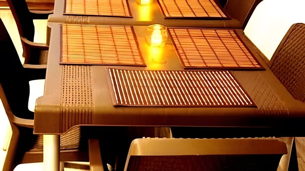 Una mesa con un mantel tejido, una vela y un objeto de vidrio.
