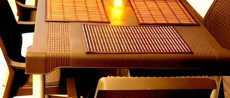 A table with a woven placemat, a candle, and a glass object.