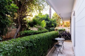 Eine Terrasse mit Tisch und Stühlen, umgeben von üppigem Grün und einem Baum.