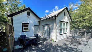 Ett tvåvåningshus med en veranda, en matplats med stolar och ett garage.