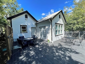 A two-story house with a deck, a dining area with chairs, and a garage.