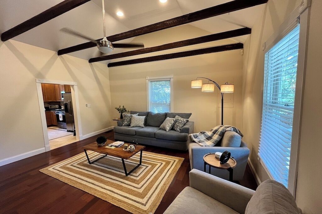 Una sala de estar con sofá, sillón, mesa de centro y lámpara.