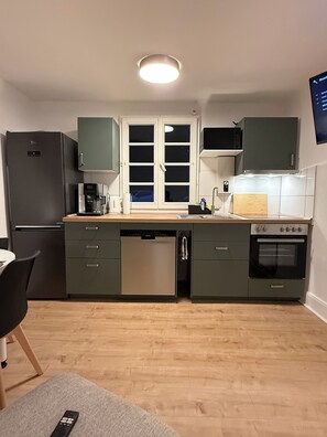 A compact kitchen with a refrigerator, dishwasher, microwave, and oven.