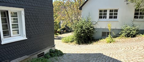 A cobblestone driveway leading to a house with a dark roof and white trim.