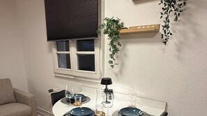 A dining area with a round table, black chairs, and a window with blinds.
