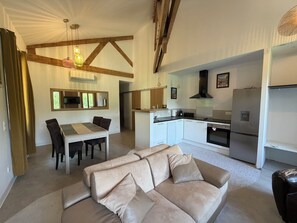 Ein modernes Wohnzimmer mit einer Couch, einem Esstisch und einer Küchenzeile mit Geräten.