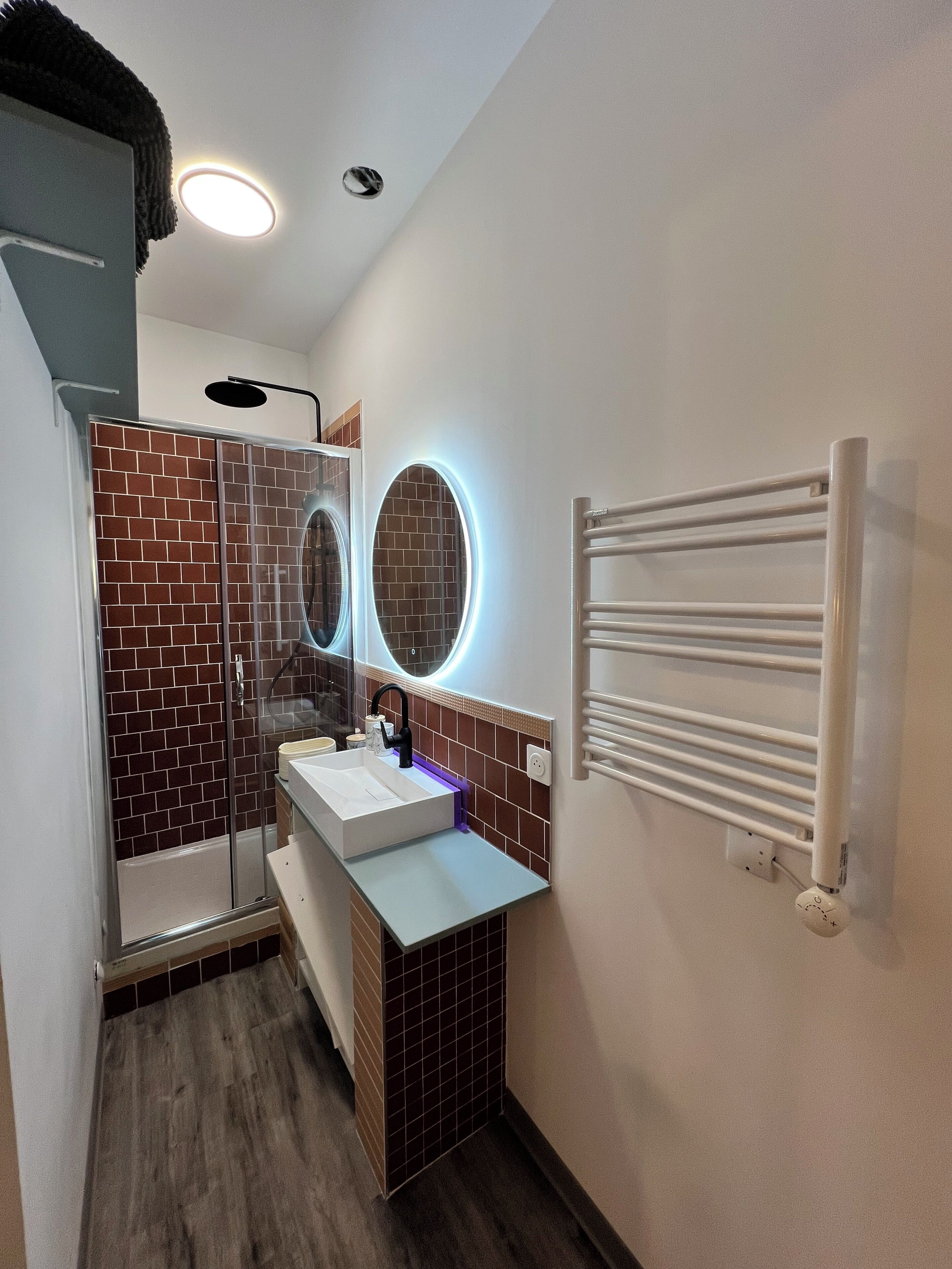 A bathroom with a shower, a sink, a mirror, and a towel rack.
