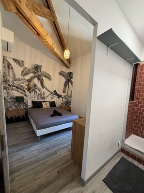Ein Schlafzimmer mit einem Bett, Holzbalken, Wandmalerei, Nachttisch und einer Pendelleuchte.
