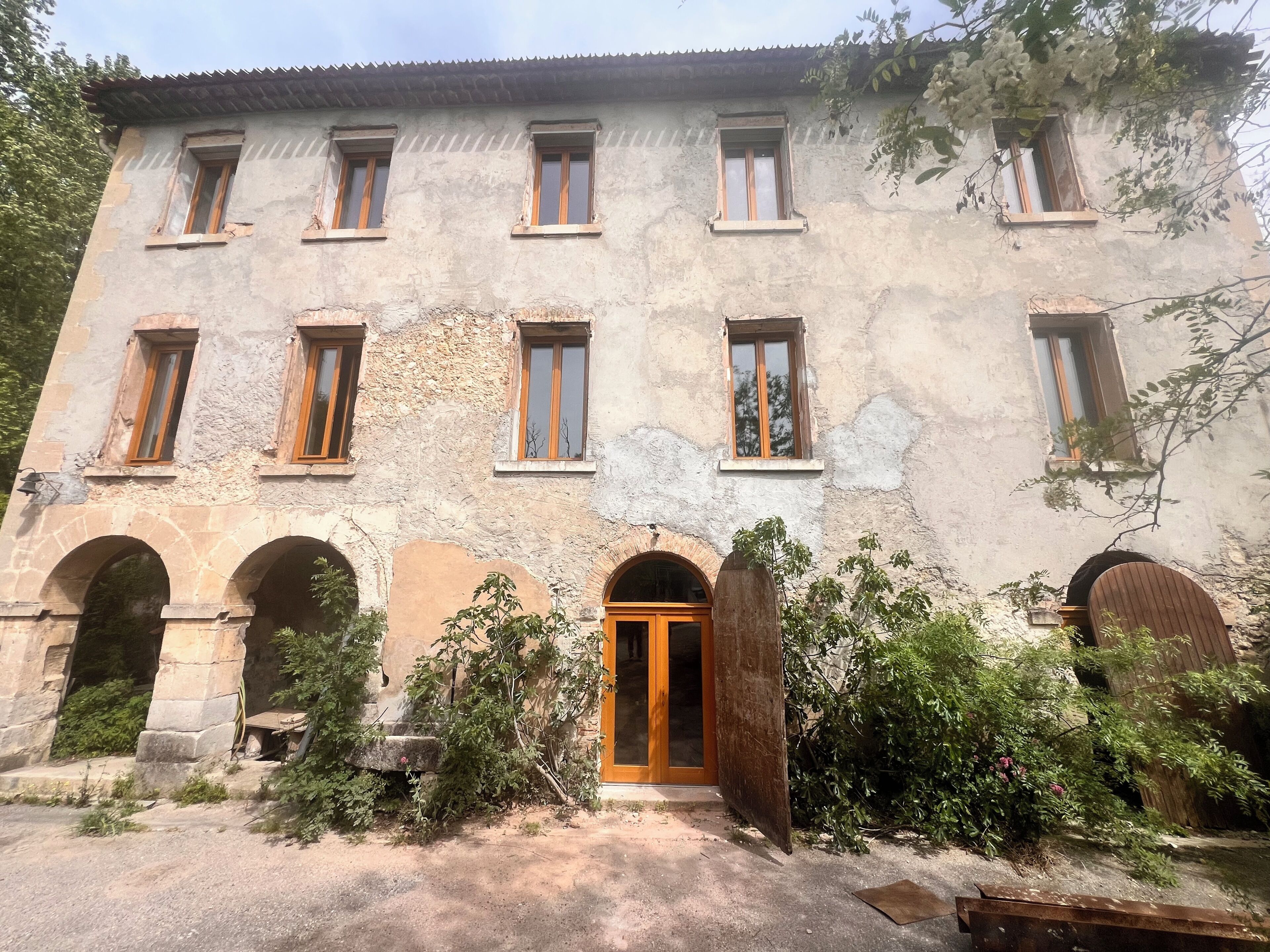 Un edificio histórico con múltiples ventanas, arcos de piedra y una puerta central de madera.