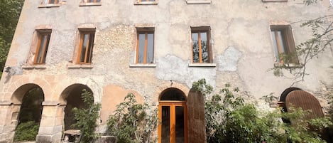 Un edificio histórico con múltiples ventanas, arcos de piedra y una puerta central de madera.