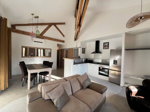 Eine moderne Küche mit integrierten Geräten, eine Essecke mit Tisch und Stühlen sowie ein Wohnbereich mit einer Couch.