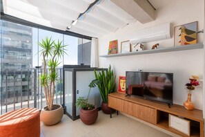 Un salon moderne avec une grande télévision, des plantes en pot et des œuvres d’art accrochées au mur.