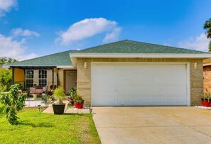 A single-story house with a garage, a covered patio, and a well-maintained lawn.