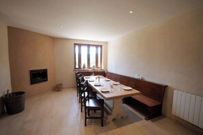 A dining area with a long table set for four, a bench, a fireplace, and a window with curtains. - 3.5-hectare private estate — heated pool, tennis and padel courts, sleeps 11 (Romans-sur-Isère)