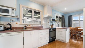 Een moderne keuken met witte kastjes, een inbouwoven, een magnetron en een raam boven de gootsteen.