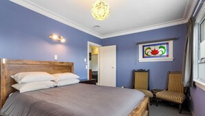 Een slaapkamer met een groot bed, een houten hoofdbord, een stoel, een spiegel en een glas-in-loodraam.