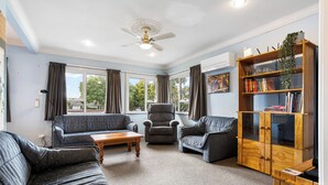 Een woonkamer met een bank, fauteuil en een houten kast vol boeken.