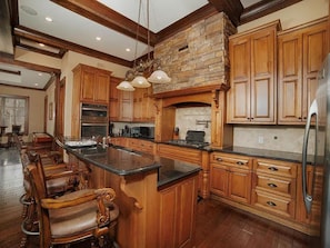 Una cocina amplia con muebles de madera, una isla central y una pared decorativa de piedra.
