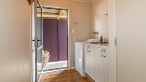 Un couloir étroit avec un plancher en bois, un réfrigérateur blanc et un petit coin cuisine comprenant un évier et des placards.