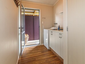 A narrow hallway with a wooden floor, a white refrigerator, and a small kitchen area with a sink and cabinets. - Mountainview Glimpse - Ohakune Holiday Home (Ohakune)
