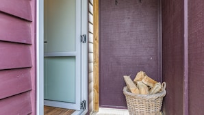 Une porte en bois, avec un panier de bois de chauffage à côté.