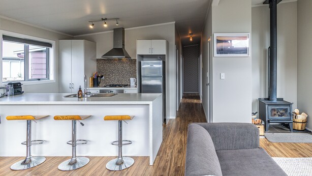 Une cuisine moderne dotée d’un îlot central, de tabourets de bar, d’une cuisinière et d’un four encastré.