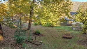 Ein Garten mit Bäumen, einem Gewächshaus und einem Haus im Hintergrund.