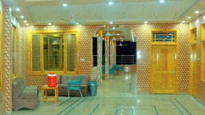 Rebuda d'hotel amb sòl de rajola, portes de fusta i zona de seients amb un sofà i cadires.