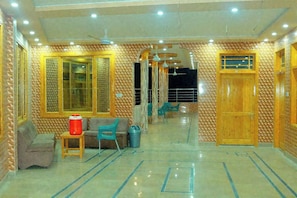 A hotel lobby with a tiled floor, wooden doors, and a seating area with a sofa and chairs. - Fantastic 9-bedroom hotel in Bahrain perfect for group stays (Bahrain)
