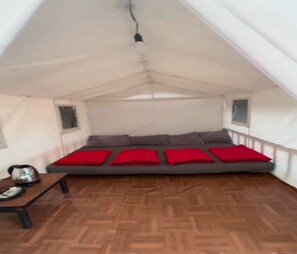 A tented room with a bed, pillows, a table with a kettle, and a window. - Cozzy Saung Singkur Riverside (bandung)