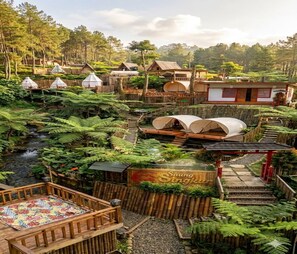 A traditional-style building with a wooden deck, a small waterfall, and a sign that reads 'Saung Dingin.' - Cozzy Saung Singkur Riverside (bandung)