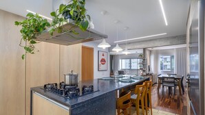 Una cocina moderna con una isla central, sillas de madera y un comedor con mesa y sillas.