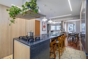 Eine moderne Küche mit einer zentralen Kochinsel, Holzstühlen und einem Essbereich mit Tisch und Stühlen.