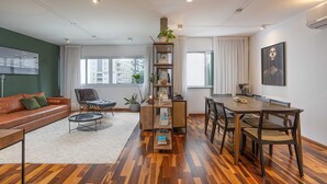 Una sala moderna con un sofá, una mesa de centro, una estantería y un comedor con sillas y una mesa.
