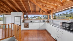 Eine moderne Küche mit weißen Schränken, Edelstahlgeräten und einer Holzbalkendecke.