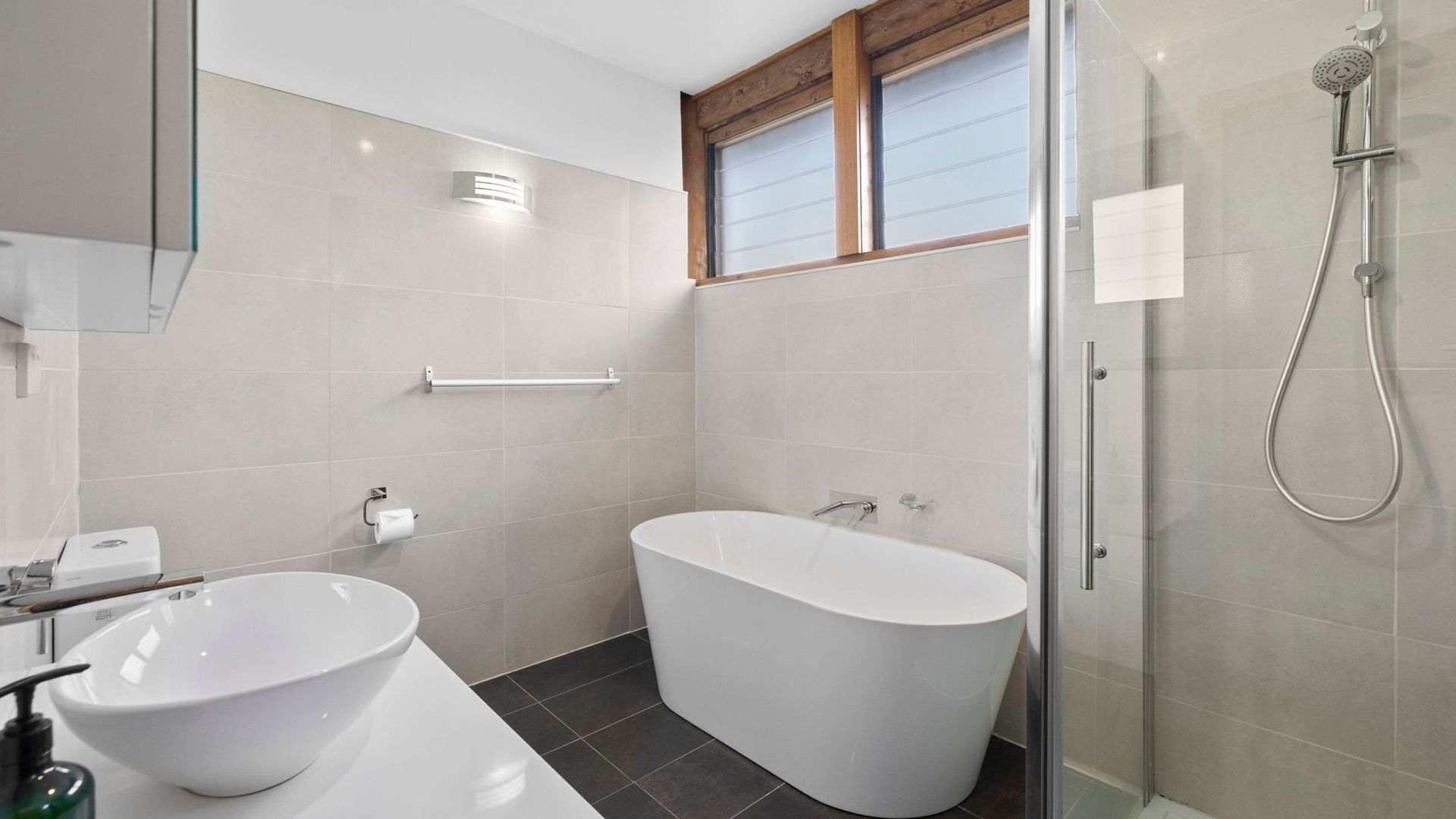 A modern bathroom with a freestanding bathtub, a glass-enclosed shower, and a white sink.