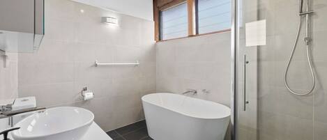 A modern bathroom with a freestanding bathtub, a glass-enclosed shower, and a white sink.