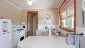 Eine kompakte Küche mit Kühlschrank, Mikrowelle, Backofen, Spüle und einem Fenster mit Aussicht.