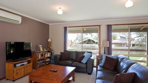 Ein Wohnzimmer mit Fernseher, Sofa, Couchtisch und Bücherregal.