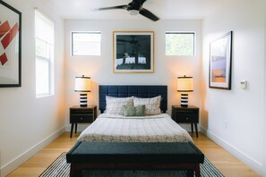 A bedroom with a bed, two bedside tables with lamps, a ceiling fan, and framed pictures on the walls. - Modern Private Quiet East Austin Studio (Austin)