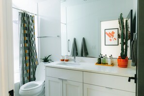 A bathroom with a toilet, sink, mirror, towel rack, and potted plants.
