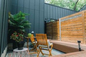 A patio area with a wooden bench, two chairs, a small table, and a potted plant. - Modern Private Quiet East Austin Studio (Austin)