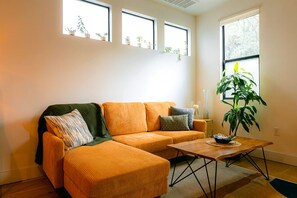 Ein Wohnzimmer mit einer Couch, einem Couchtisch und einer Zimmerpflanze.