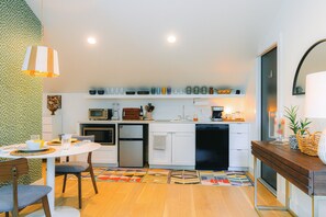 A modern kitchen with white cabinets, a dining table with chairs, and a patterned rug.